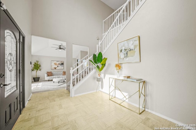 entrance foyer featuring baseboards, stairs, and a towering ceiling