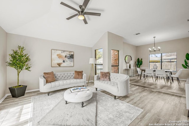 living area featuring baseboards, ceiling fan with notable chandelier, visible vents, and light wood-type flooring