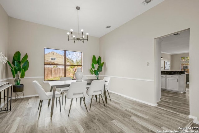 dining room featuring a notable chandelier, baseboards, and wood finished floors