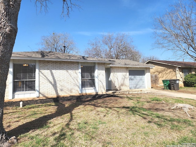 back of house featuring brick siding, an attached garage, concrete driveway, and a yard