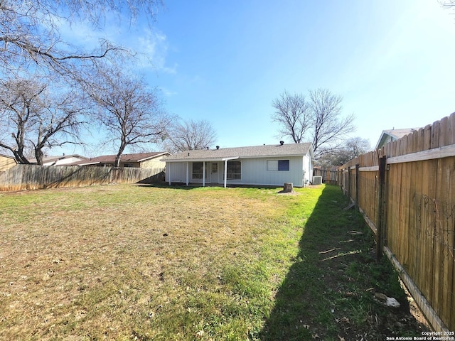 back of house with a fenced backyard and a yard