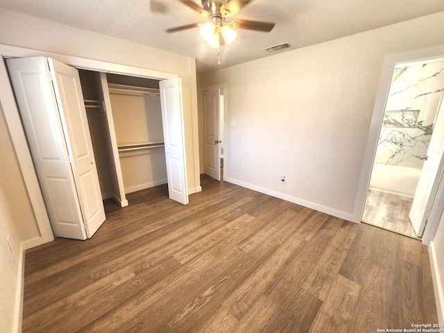 unfurnished bedroom featuring visible vents, a ceiling fan, ensuite bathroom, wood finished floors, and baseboards