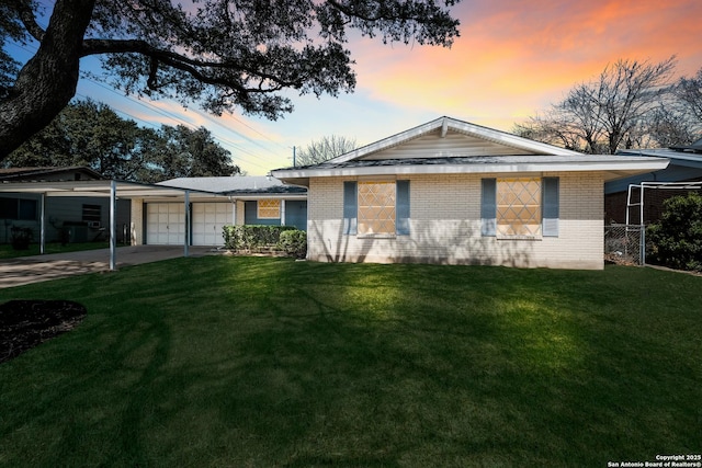 ranch-style home with a front lawn, concrete driveway, a garage, a carport, and brick siding