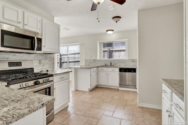 kitchen with a sink, stainless steel appliances, white cabinets, and decorative backsplash