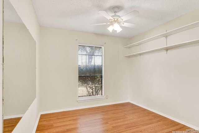 spare room featuring baseboards, light wood-style floors, ceiling fan, and a textured ceiling