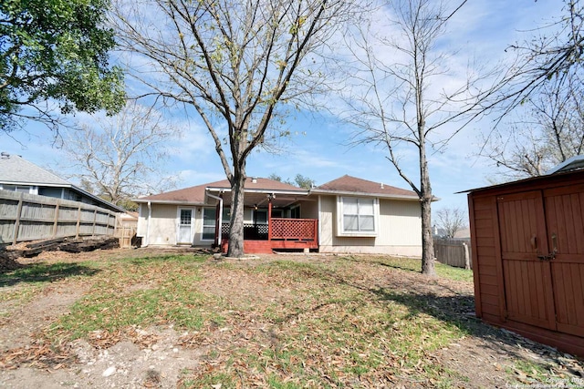 back of property with a storage shed, an outdoor structure, and fence