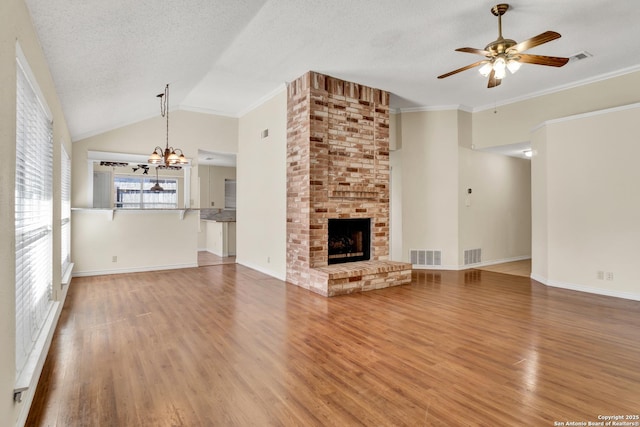 unfurnished living room featuring wood finished floors, visible vents, a fireplace, a textured ceiling, and ceiling fan with notable chandelier