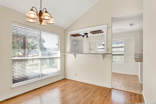 kitchen featuring light wood finished floors, plenty of natural light, a kitchen bar, and vaulted ceiling