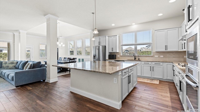 kitchen with dark wood finished floors, a sink, decorative backsplash, stainless steel appliances, and open floor plan