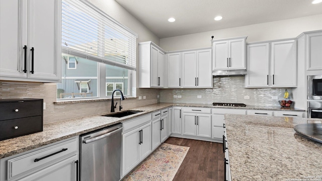 kitchen featuring a sink, under cabinet range hood, stainless steel appliances, white cabinetry, and dark wood-style flooring