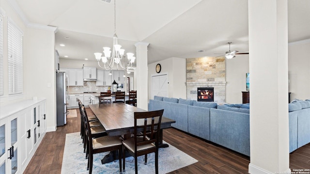 dining area with dark wood-style floors, baseboards, ornamental molding, ceiling fan with notable chandelier, and a large fireplace