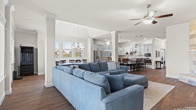 living area featuring ceiling fan with notable chandelier, dark wood-style floors, crown molding, decorative columns, and baseboards