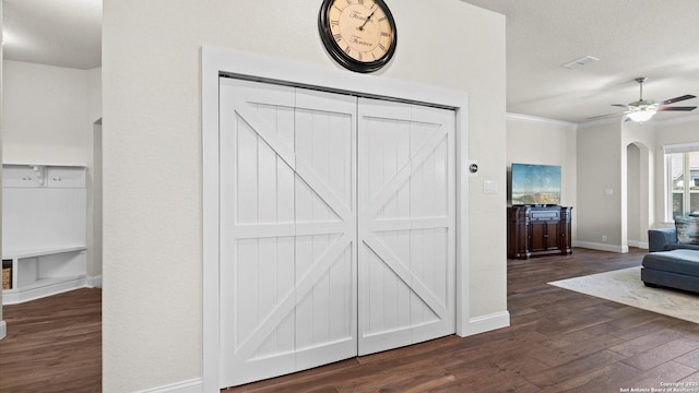 interior space with dark wood finished floors, arched walkways, crown molding, baseboards, and ceiling fan