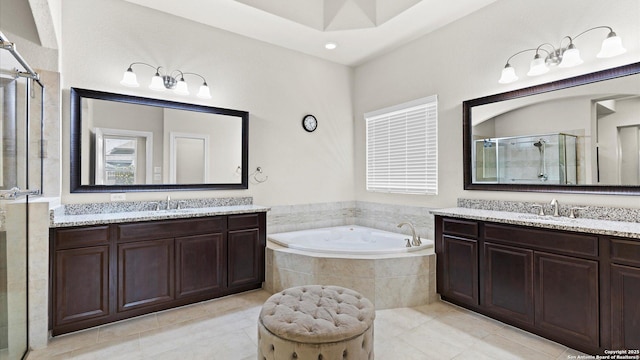 bathroom with a sink, a garden tub, two vanities, and a stall shower