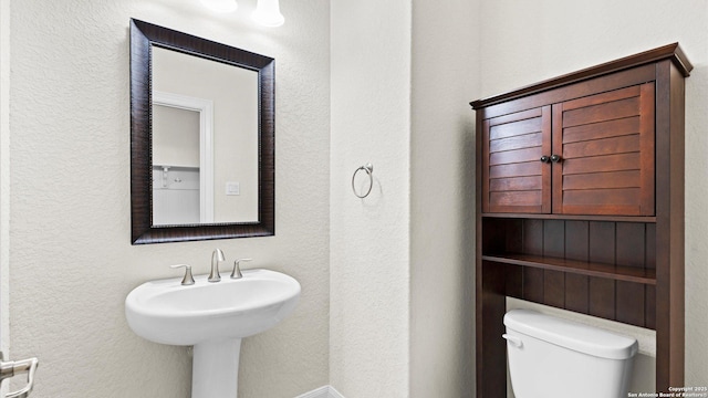 bathroom with toilet and a textured wall