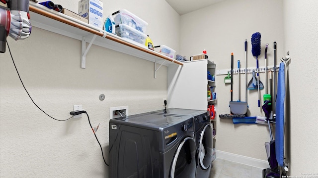 washroom featuring washing machine and clothes dryer, laundry area, tile patterned flooring, and baseboards