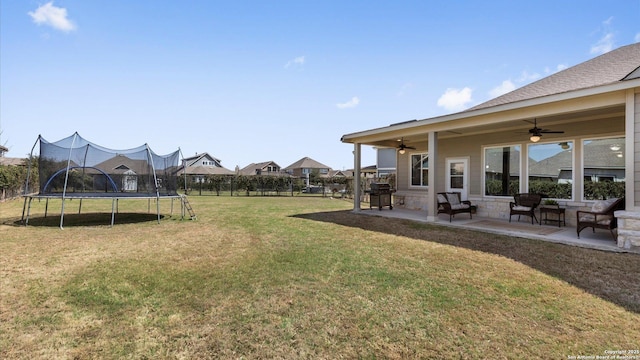 view of yard featuring fence, a trampoline, ceiling fan, and a patio area