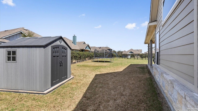 view of yard with an outdoor structure, a trampoline, and a storage unit