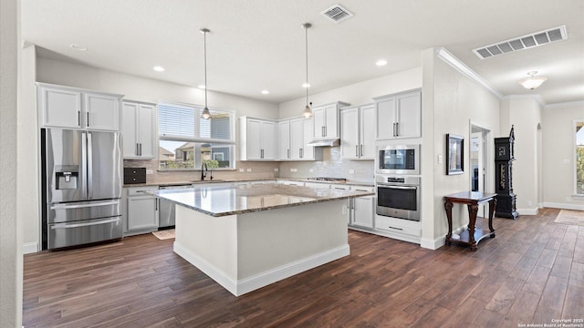 kitchen with visible vents, a sink, dark wood-type flooring, appliances with stainless steel finishes, and a center island