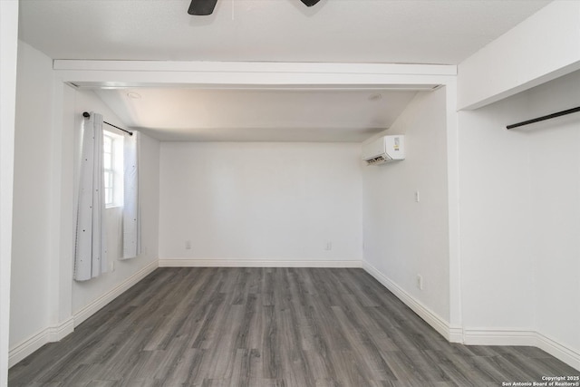 unfurnished room with an AC wall unit, wood finished floors, baseboards, and ceiling fan