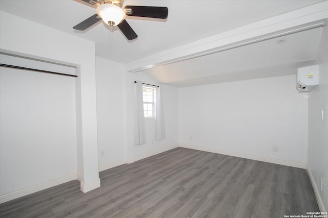 unfurnished bedroom featuring vaulted ceiling with beams, ceiling fan, baseboards, an AC wall unit, and wood finished floors