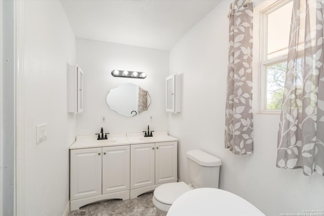 bathroom featuring a sink, toilet, and double vanity