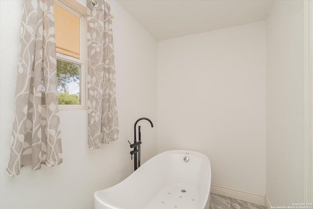 bathroom featuring baseboards and a freestanding bath