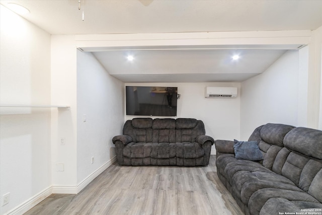 living area with a wall mounted air conditioner, baseboards, and light wood-style floors