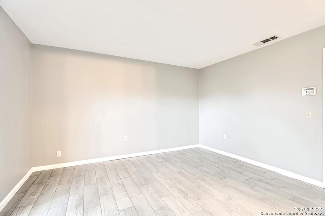 unfurnished room with visible vents, baseboards, and wood finished floors