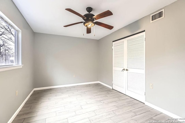 unfurnished bedroom with wood finished floors, visible vents, a closet, and baseboards