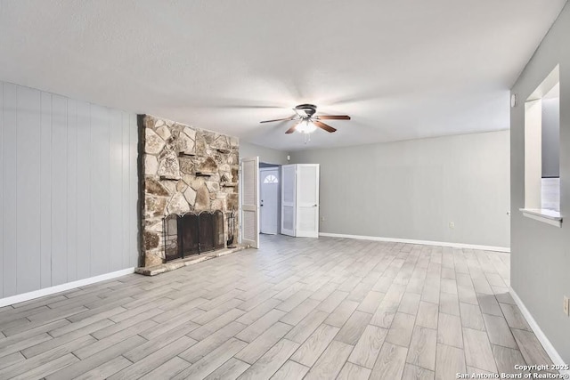 unfurnished living room with baseboards, a ceiling fan, wood finished floors, and a fireplace