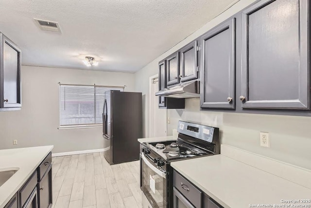 kitchen with under cabinet range hood, visible vents, stainless steel appliances, and light countertops