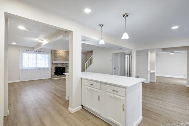 kitchen with light wood-style flooring, open floor plan, white cabinets, and pendant lighting