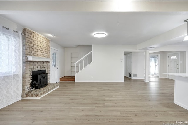 unfurnished living room featuring stairs, baseboards, visible vents, and light wood finished floors