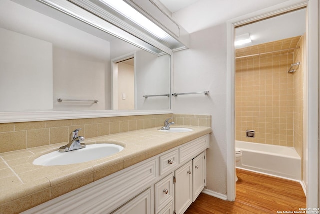 bathroom featuring double vanity, toilet, wood finished floors, and a sink