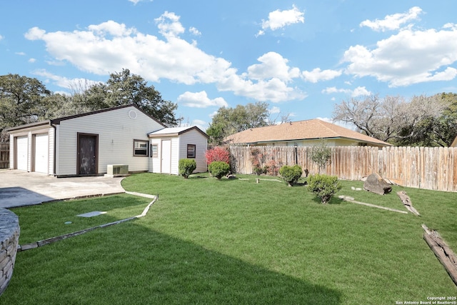 view of yard featuring an outbuilding, central AC unit, a garage, and fence