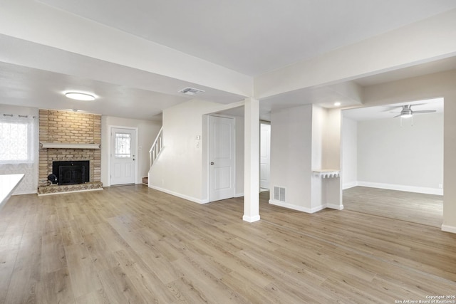 unfurnished living room with visible vents, stairs, and wood finished floors