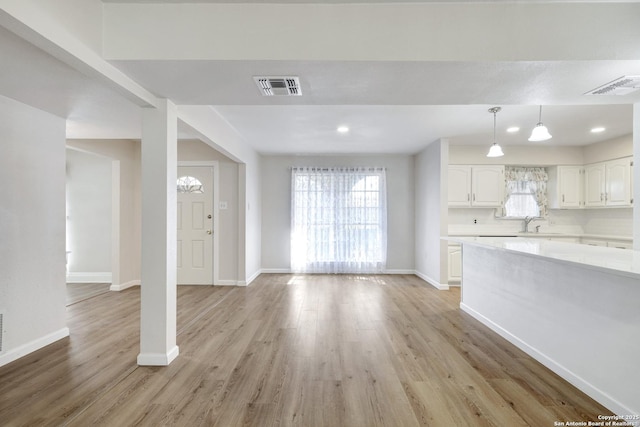 unfurnished living room with visible vents, light wood-style floors, and a healthy amount of sunlight