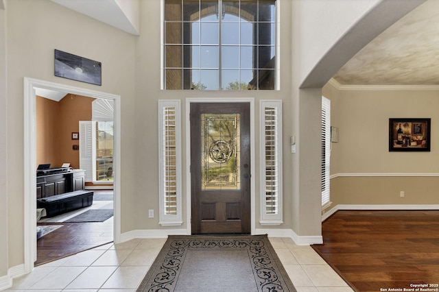 entryway featuring light tile patterned floors, baseboards, plenty of natural light, and ornamental molding