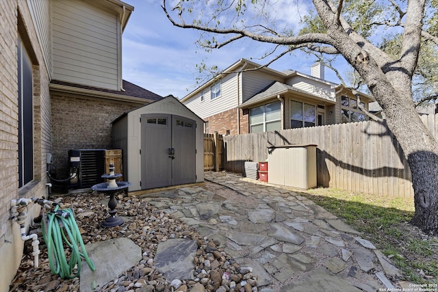 view of patio with an outbuilding, central AC, a fenced backyard, and a shed