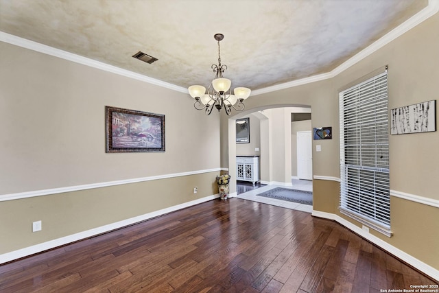 empty room with visible vents, ornamental molding, baseboards, and hardwood / wood-style floors