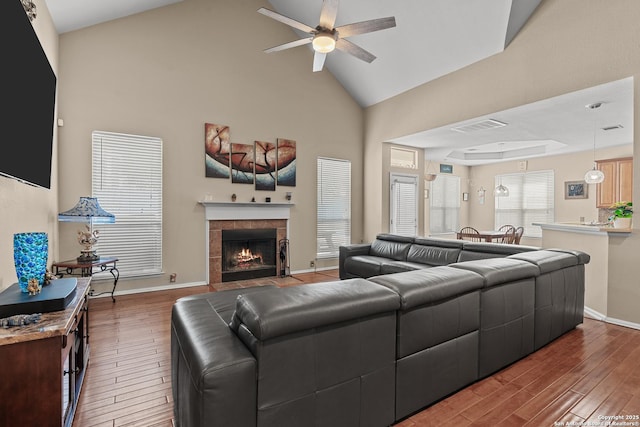 living room with ceiling fan, wood finished floors, visible vents, and a tile fireplace