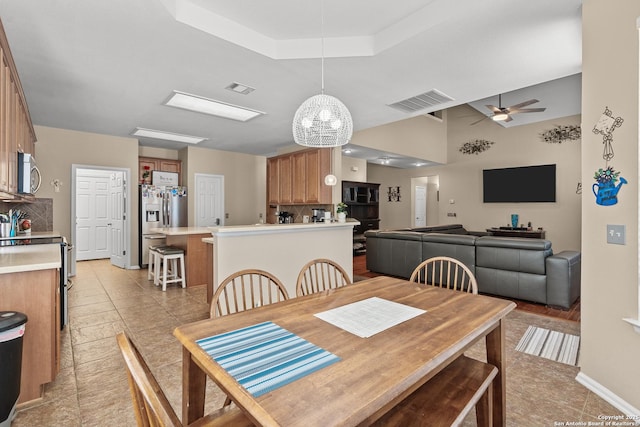 dining area featuring a tray ceiling, visible vents, a ceiling fan, and light tile patterned floors