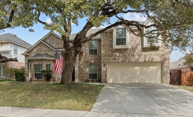 traditional-style house featuring concrete driveway, a garage, fence, and brick siding