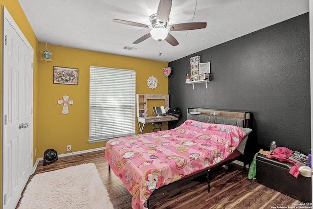 bedroom featuring visible vents, ceiling fan, baseboards, and wood finished floors