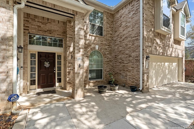 property entrance featuring a garage, brick siding, and driveway