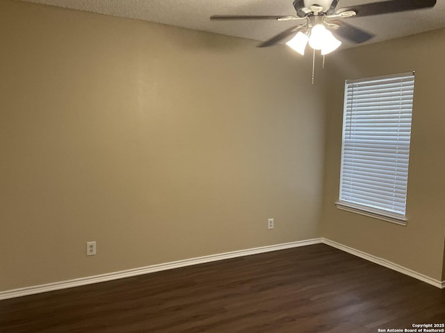 spare room with dark wood-type flooring, a ceiling fan, baseboards, and a textured ceiling