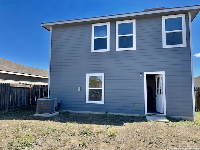 rear view of house with a yard, fence, and central AC