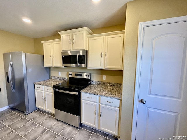 kitchen with tile patterned flooring, stone countertops, appliances with stainless steel finishes, and white cabinetry