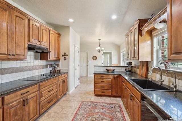 kitchen featuring under cabinet range hood, a notable chandelier, brown cabinetry, and a sink